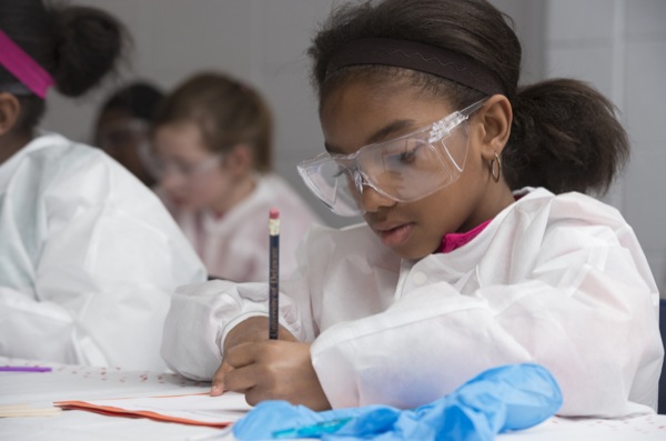 young girl in lab coat writing